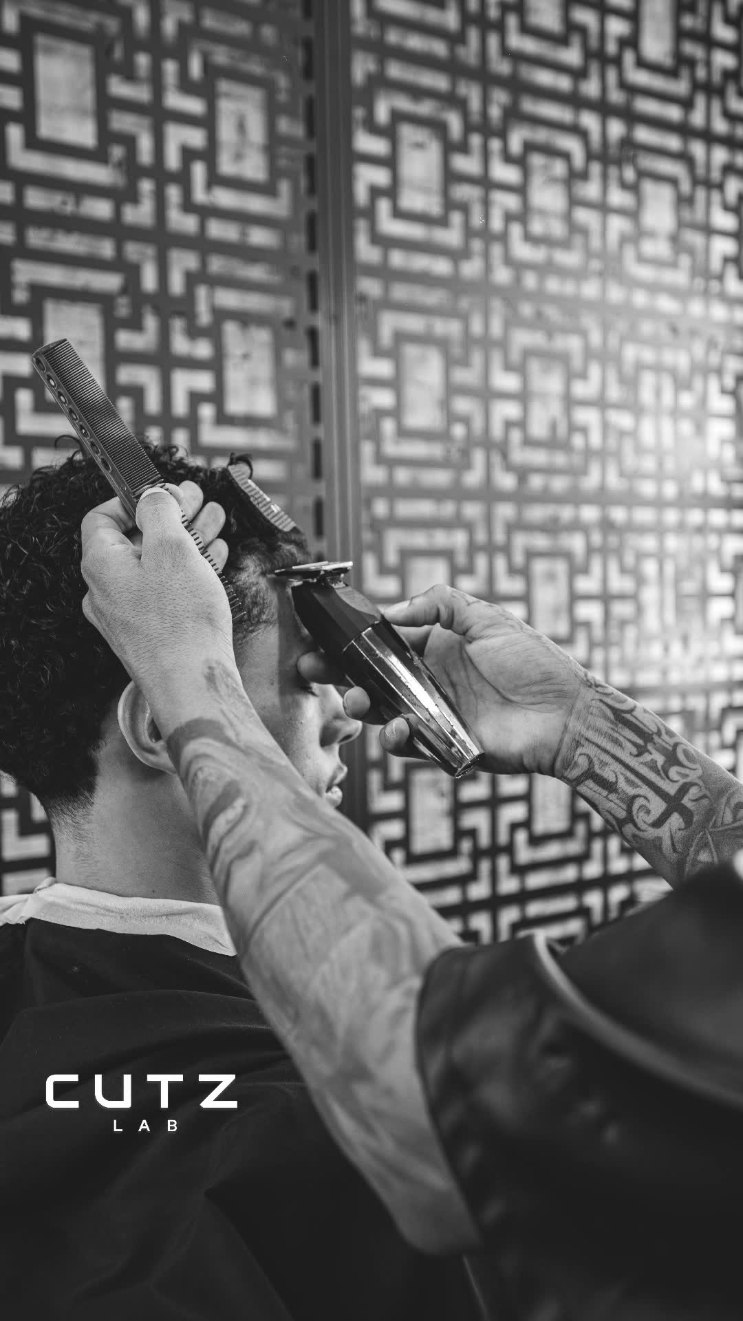 Máquina e pente em ação num corte de cabelo cacheado