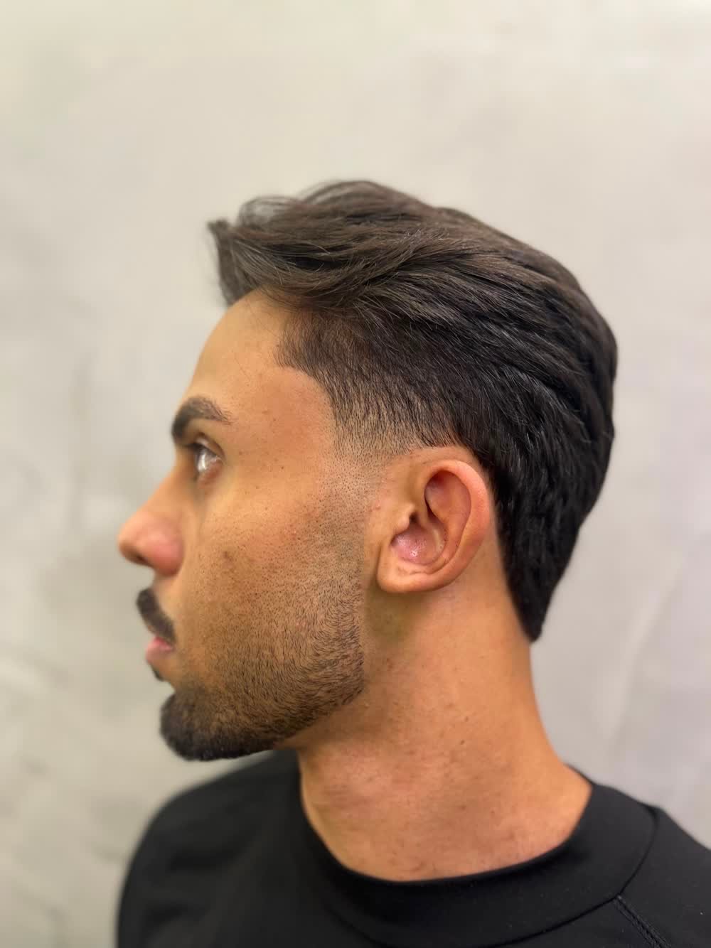 Resultado de corte masculino com taper fade e topo texturizado, visto de perfil