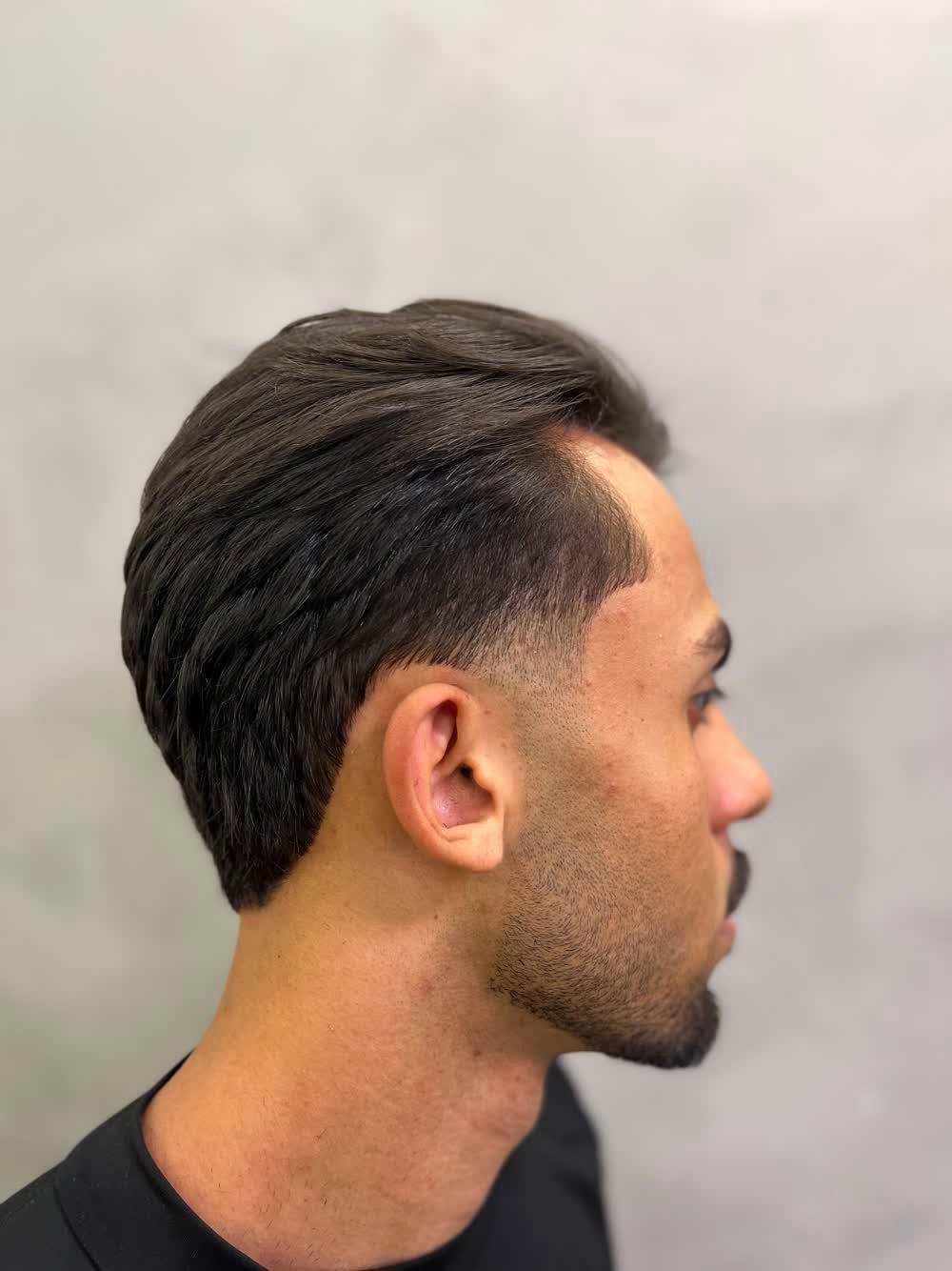 Perfil do corte masculino finalizado, com degradê e barba alinhada