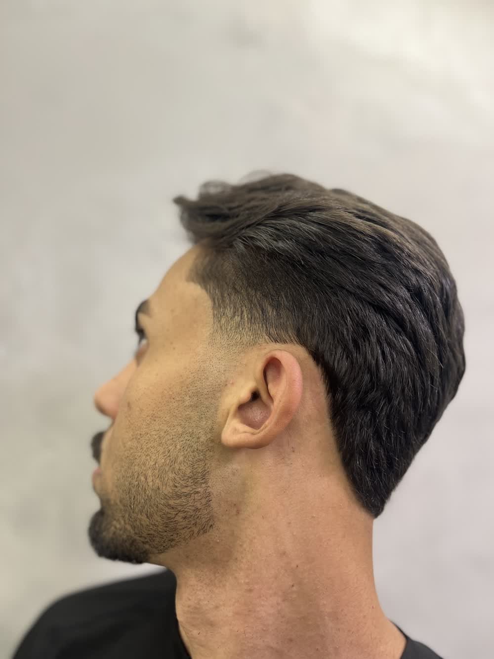 Corte masculino escuro com degradê baixo e topo penteado para trás